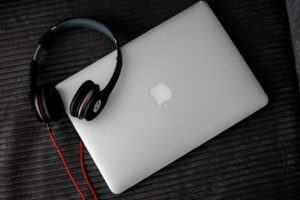 Macbook laptop with headphones on a table. Learn how to grow your Soundcloud following